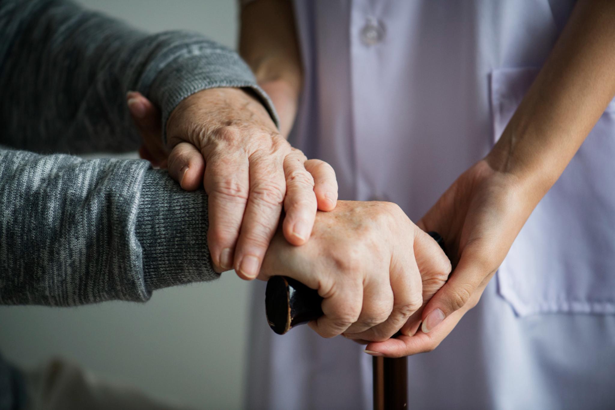 An old woman and a young woman holding hands